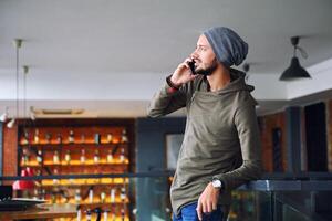 Young handsome hipster man using smartphone in cafe photo