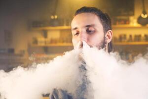 el hombre fumar un electrónico cigarrillo a el vape tienda. de cerca. foto