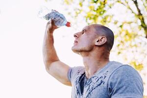 joven atleta es refrescante él mismo con agua, deporte y sano estilo de vida foto