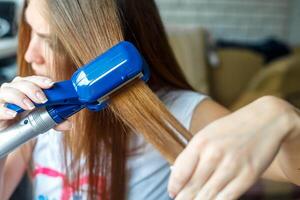 Hairdresser hairstyle models using the straightener. Closeup. Selective focus. photo