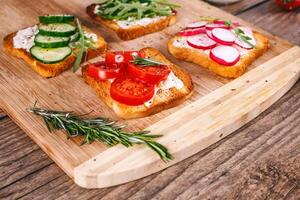 Four sandwiches with fresh vegetables, tomatoes, cucumbers, radish and arugula on a wooden background. Homemade butter and toast. selective focus. photo