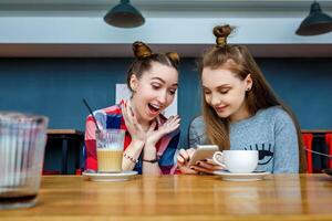 two young beautiful hipster women sitting at cafe, talking, flirty, stylish trendy outfit, europe vacation, street style, happy, having fun, smiling, positive mood photo