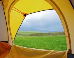 Kind from tent on lawn with green grass photo