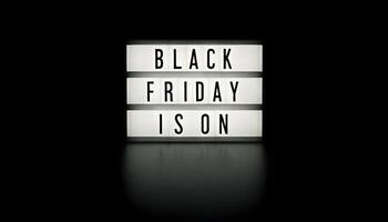 A lightbox with the words BLACK FRIDAY IS ON illuminated on a dark background photo