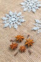 Snowflakes and anise stars on natural sackcloth background. Winter holidays concept photo