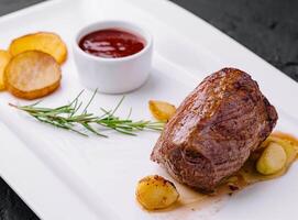 fried medallion with garlic, potatoes and rosemary photo