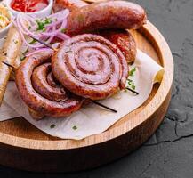 Grilled sausages on a wooden board with sauce photo