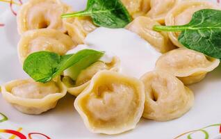 Boiled dumplings with basil on plate photo