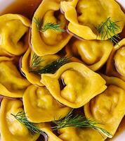 Filled tortellini with herbs close up photo