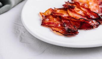 Plate with tasty bacon slices on stone photo