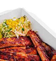 Tasty grilled ribs with vegetables in box photo