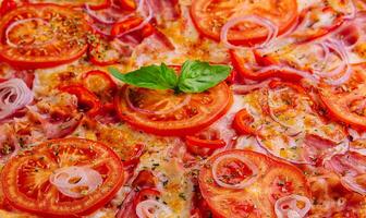 Pizza con tocino cebollas y Tomates foto