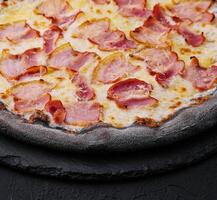 black dough pizza with cheese and ham photo