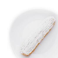 eclair in white glaze and coconut flakes photo