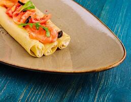 Delicious thin pancakes with salmon and sour cream on plate photo