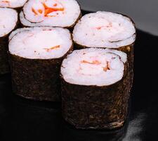 Sushi rodar maki con camarón en un negro plato foto