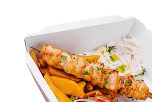 Chicken skewers with potatoes and tomato and onion salad photo