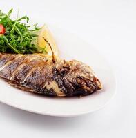 Baked sea bream fish with arugula salad and tomatoes photo