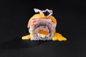 Gourmet sushi roll with mango sauce on black background photo