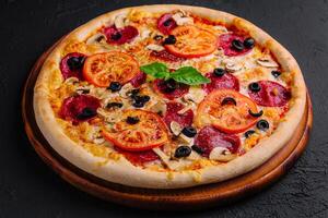 Delicious homemade supreme pizza on wooden board photo