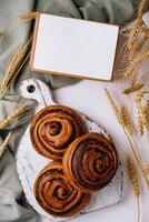 Artisan cinnamon rolls on wooden board with blank recipe book photo