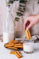 Hand dipping biscuit into milk glass photo