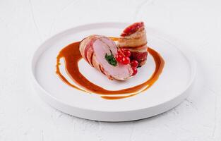 Gourmet pork tenderloin with berry garnish and sauce photo