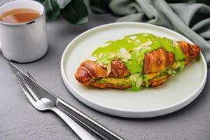 Green matcha croissant on plate with tea photo