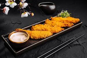 Crispy breaded shrimp with dipping sauce and cherry blossoms photo