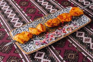 Traditional marinated grilled chicken skewers on ornate plate photo