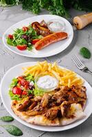 Delicious grilled chicken and sausage with fresh salad and fries photo