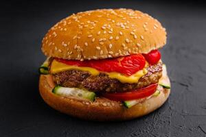 Delightful gourmet cheeseburger on dark background photo