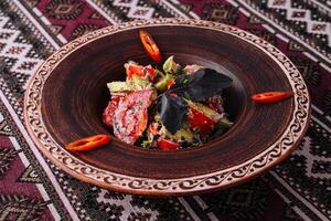 Traditional spicy tomato salad on ethnic pattern tablecloth photo