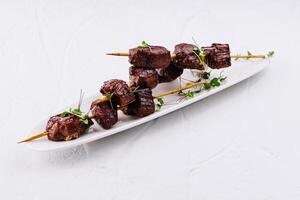 Gourmet grilled steak skewers on white plate photo