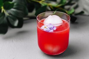 Refreshing watermelon cocktail with ice ball and edible flower photo