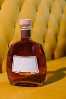 elite cognac or brandy bottle on yellow textured background photo