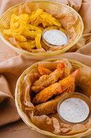 Crunchy breaded shrimp with dipping sauce and chips photo