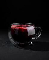 Elegant glass of red tea on dark background photo