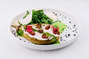 Gourmet stuffed eggplant with fresh greens plate photo