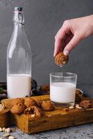 Hand dipping cookie in milk glass photo