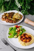 Two plates of nutritious meals with salad, grilled skewers, and mashed potatoes on a textured background photo