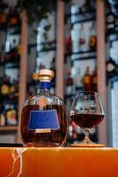 Elegant brandy bottle and glass on bar counter photo