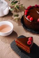 Elegant raspberry chocolate cake slice with tea setup photo