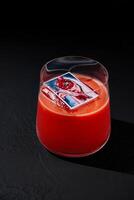 Elegant red cocktail with ice cube on dark background photo