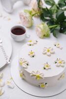 Elegant white floral cake with tea setting photo