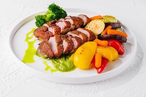 Grilled pork tenderloin with roasted vegetables and sauce photo