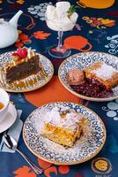Assorted desserts with ice cream on a colorful tablecloth photo