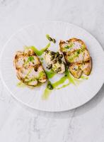 Grilled chicken breast with pesto drizzle on white plate photo