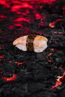 Shrimp sushi on a black lava rock with glowing red textures photo