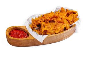 Spicy potato wedges with dip on wooden platter photo